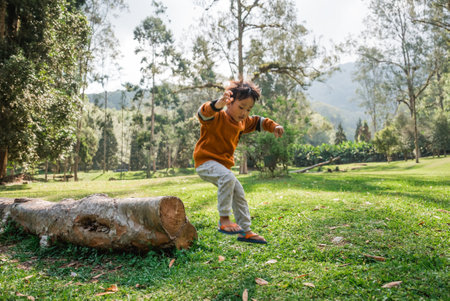 A young child joyfully explores nature, skillfully balancing on a log in a beautiful settingの写真素材
