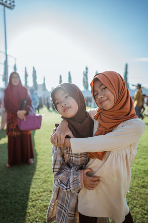 Two close friends share a warm embrace in a colorful outdoor setting on a sunny dayの写真素材