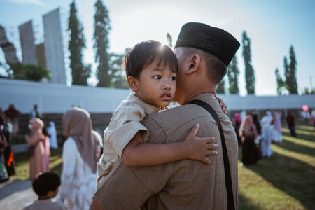 A loving father warmly embraces his child during a joyful outdoor celebration filled with happinessの写真素材