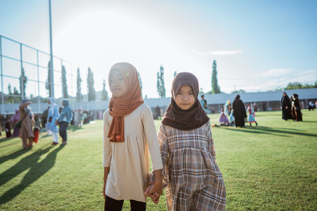 Two girls in colorful hijabs walk cheerfully outdoors, enjoying their time together