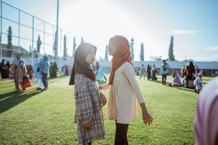 In a bright park lit by sunlight, two cheerful girls play joyfully, surrounded by laughterの写真素材
