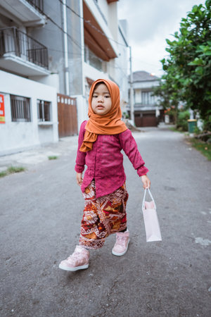A cheerful young girl in colorful attire happily walks down a city streetの写真素材