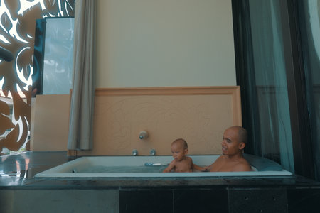 A peaceful and serene moment featuring an adult and a baby enjoying a cozy bath time settingの写真素材
