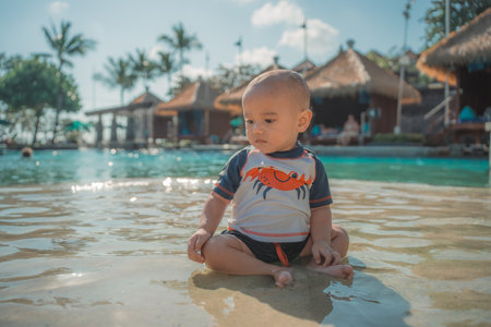 A charming and adorable baby immersing herself in the refreshing water at a sunny beach resortの写真素材