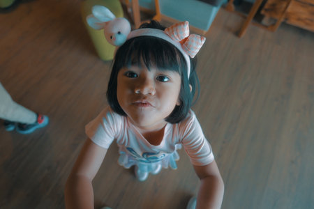 A joyful little girl is captured in a playful moment with a charming pose radiating innocenceの写真素材