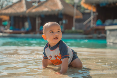 A happy baby delights in crawling through the shallow water at a beautiful resort location