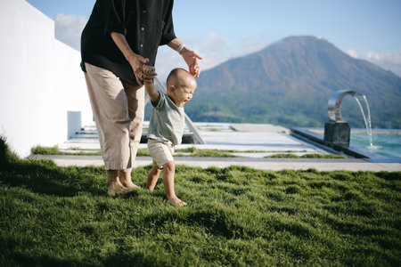 In a beautiful, scenic outdoor setting, a loving grandparent assists a bright child in walkingの写真素材