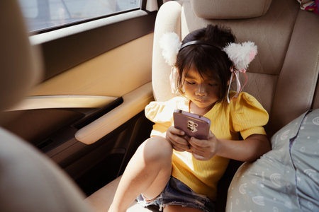 A girl enjoys listening to music through her headphones while sitting comfortably in a carの写真素材