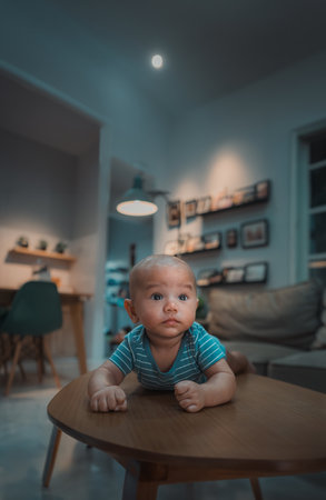 A curious baby is lying on the coffee table in a stylish living space, creating warmthの写真素材
