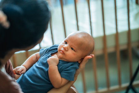 A loving parent gently cradles a cute baby indoors, creating a warm and affectionate sceneの写真素材