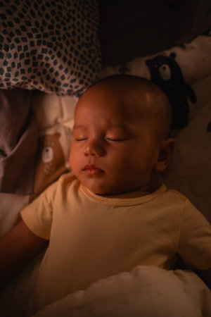 A tiny baby is peacefully sleeping in a cozy bed, resting with a soft teddy bear nestled on the...