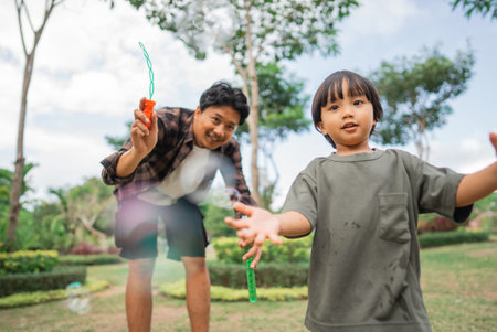 a boy catches bubbles while playing with dad at the park in the afternoonの写真素材