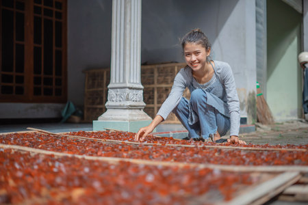 A girl joyfully sorts colorful dried fruits in a sunny outdoor space surrounded by natureの写真素材