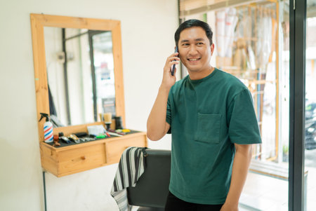 In a barber shop, a man is engaging in a conversation while speaking on his cell phone, surrounded by the vibrant atmosphere of the spaceの写真素材
