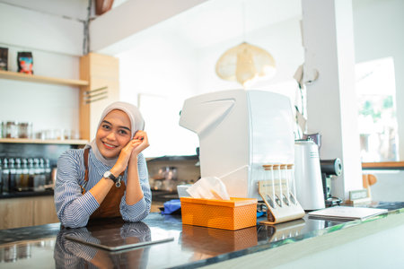 Indonesian woman in hijab shop owner sitting in coffee shopの写真素材