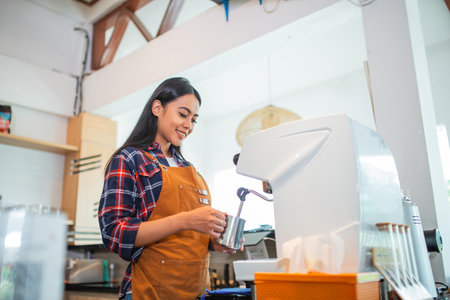female waitress wearing apron making coffee using coffee maker at coffee shopの写真素材