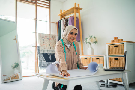 Asian woman Muslim fashion designer at work creating a new design in a workshopの写真素材