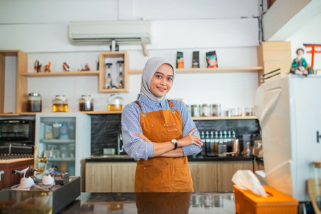 beautiful woman in hijab cafe owner wearing apron standing in coffee cafeの写真素材