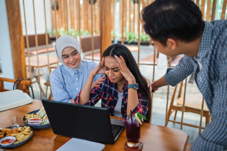 Group of young Asian students face problems when using a laptop computer together in a coffee shopの写真素材