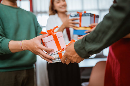 Friends joyfully exchanging beautifully wrapped gifts amidst a vibrant and festive settingの写真素材