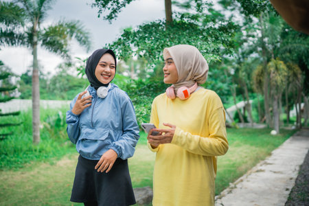 Two young women with headphones enjoy a joyful moment in a vibrant green settingの写真素材