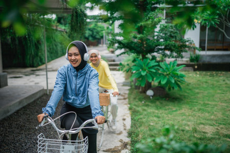 indonesian veiled women with headphones on bicycle on bike path lane in the parkの写真素材