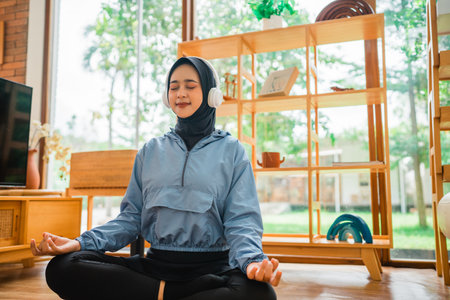A young woman meditates peacefully with headphones in a serene environment promoting calmの写真素材