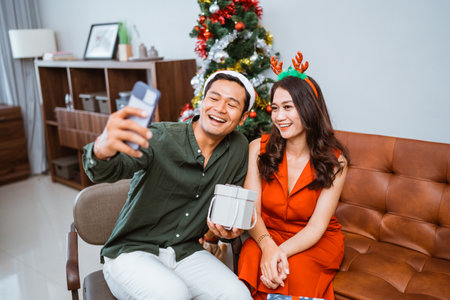 A joyful and happy couple taking a selfie together while fully enjoying the festive spiritの写真素材