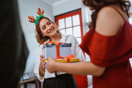 Friends joyfully exchanging beautifully wrapped gifts during a cheerful holiday celebrationの写真素材
