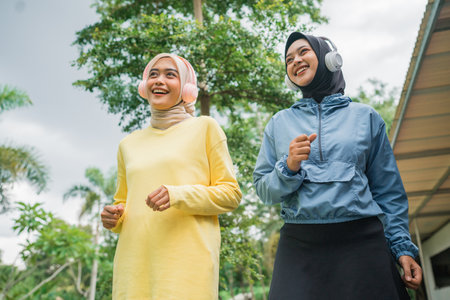 Two energetic women happily enjoy jogging together in a lush, vibrant, green outdoor settingの写真素材