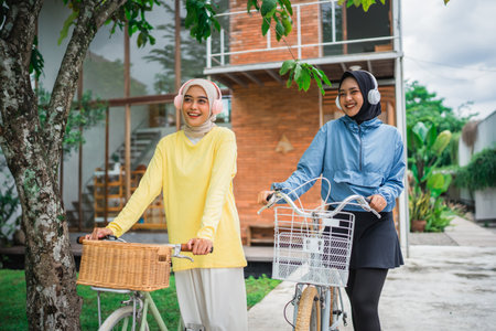 Two fashionable women enjoying a day out with bicycles in a vibrant neighborhood.の写真素材