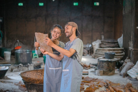Two artisans enjoy their craft in a rustic workshop filled with various materialsの写真素材