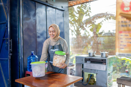 A joyful and cheerful woman busily prepares a variety of delicious snacks in her cozy food stallの写真素材