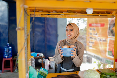 A cheerful vendor showcases fresh, organic eggs at a colorful market filled with happy peopleの写真素材