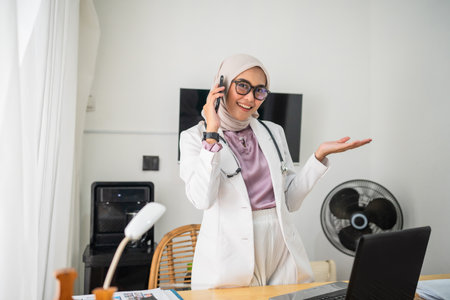 A cheerful woman in a stylish outfit is on a phone call in a chic, elegant office spaceの写真素材