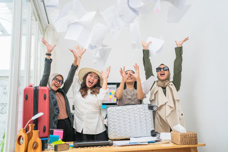 In a cheerful office, women toss papers joyfully during a lively celebration of teamworkの写真素材