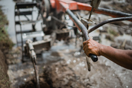 A farmer skillfully drives a powerful tractor, cultivating rich soil on the farmlandの写真素材