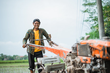 A hardworking man skillfully operates a tractor on fertile farmland for effective cultivationの写真素材