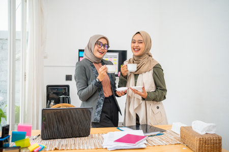 Two women bond over coffee in a bright, stylish workspace, enjoying their time togetherの写真素材