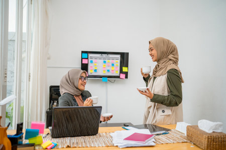 Two focused women engage in an animated conversation in a bright, modern workspace settingの写真素材
