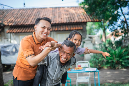 potrait of happy grandfather piggyback his cute granddaughterの写真素材