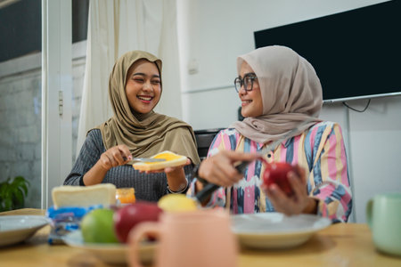 Two close friends enjoy a casual meal together, filled with hearty laughter at homeの写真素材