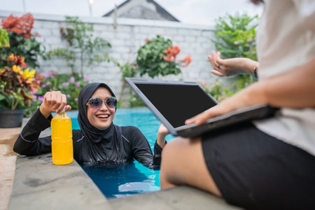 Relaxing by the poolside with modern tech and refreshing drinks for some quality timeの写真素材