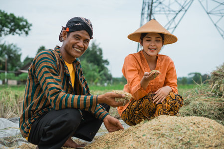Farmers proudly showcasing freshly harvested rice in a lush green, vibrant fieldの写真素材