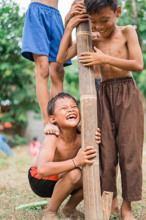 children scream to bear the weight on their shoulders during cooperation in the betel nut climbing competitionの写真素材