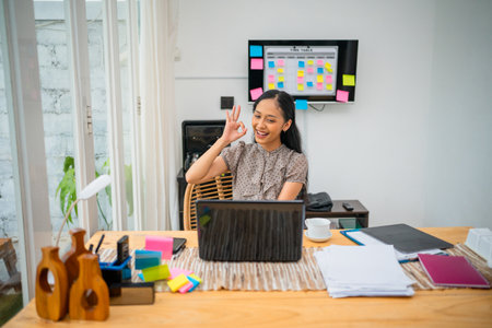 A joyful woman video calling from her stylish home office that inspires productivityの写真素材
