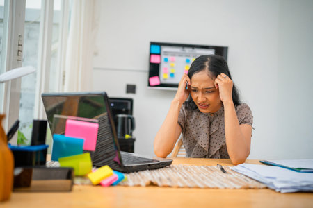 A woman feels overwhelmed and stressed while working at her home desk, facing many challenges