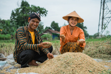 Two dedicated farmers proudly showcasing their bountiful rice harvest in a beautiful, fertile fieldの写真素材