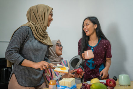 Three friends enjoy cooking tasty meals and sharing laughter in a warm, vibrant kitchenの写真素材