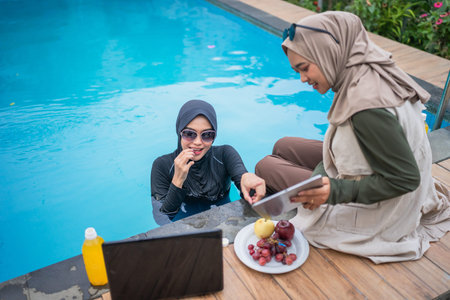 Two close friends enjoy a delightful day by the poolside, sharing food and laughterの写真素材